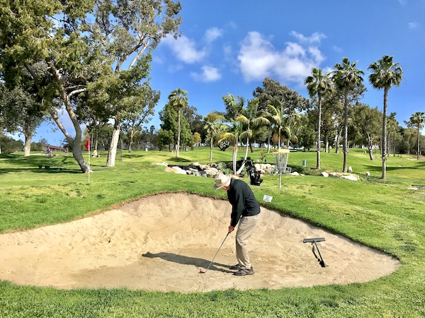 active senior man hitting out of a sand trap